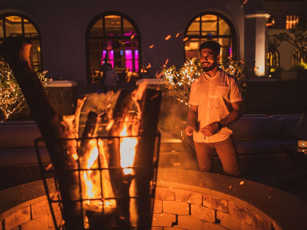 a man standing in front of a fire pit at Grand Hyatt Goa in Panaji a man standing in front of a fire pit at Grand Hyatt Goa in Panaji