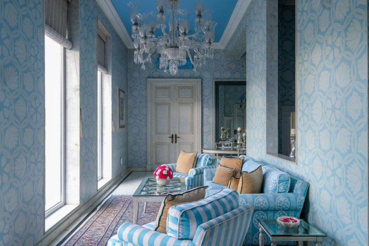 a living room with two blue couches and a chandelier at Rajmahal Palace RAAS in Jaipur