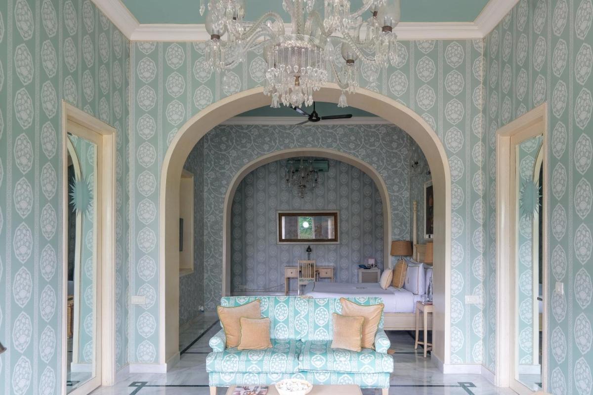 a bedroom with a bed and a chandelier and a couch at Rajmahal Palace RAAS in Jaipur