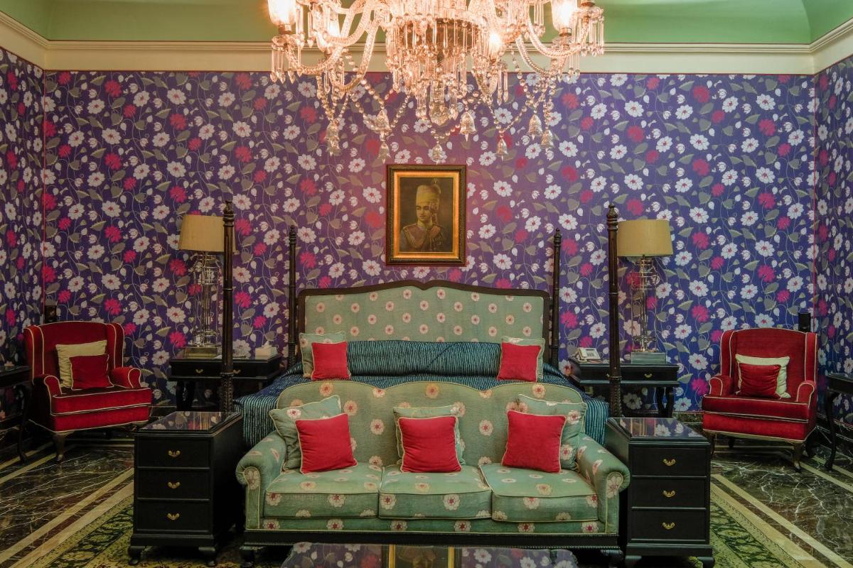 a bedroom with a bed and two red chairs at Rajmahal Palace RAAS in Jaipur