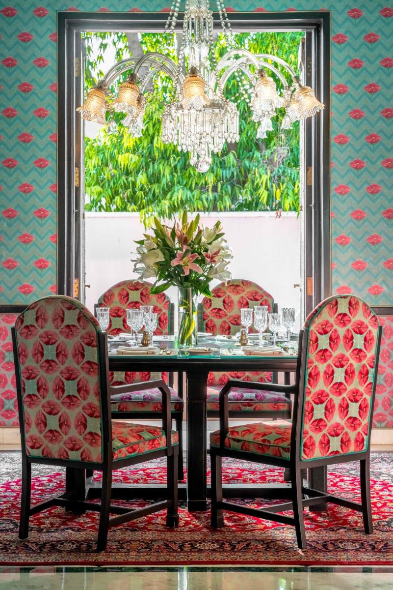 a dining room with a table with chairs and a chandelier at Rajmahal Palace RAAS in Jaipur