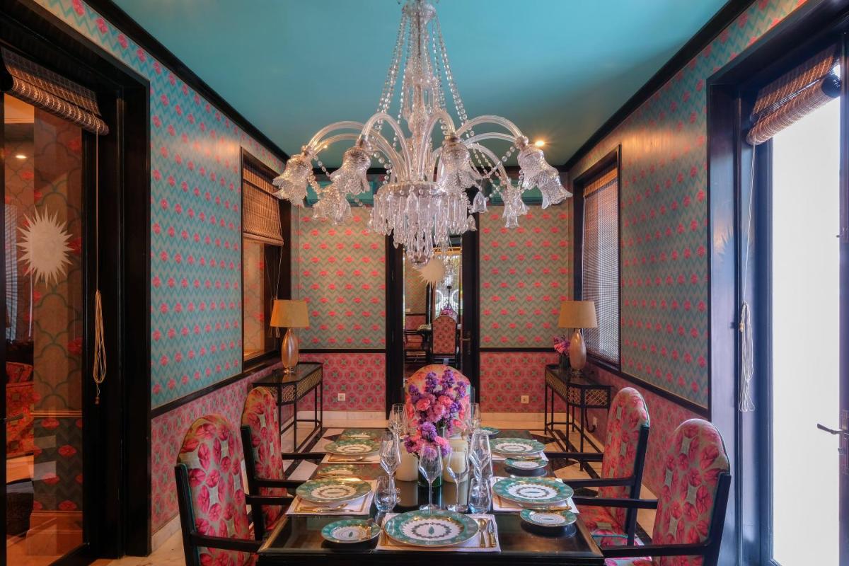 a dining room with a table and chairs and a chandelier at Rajmahal Palace RAAS in Jaipur