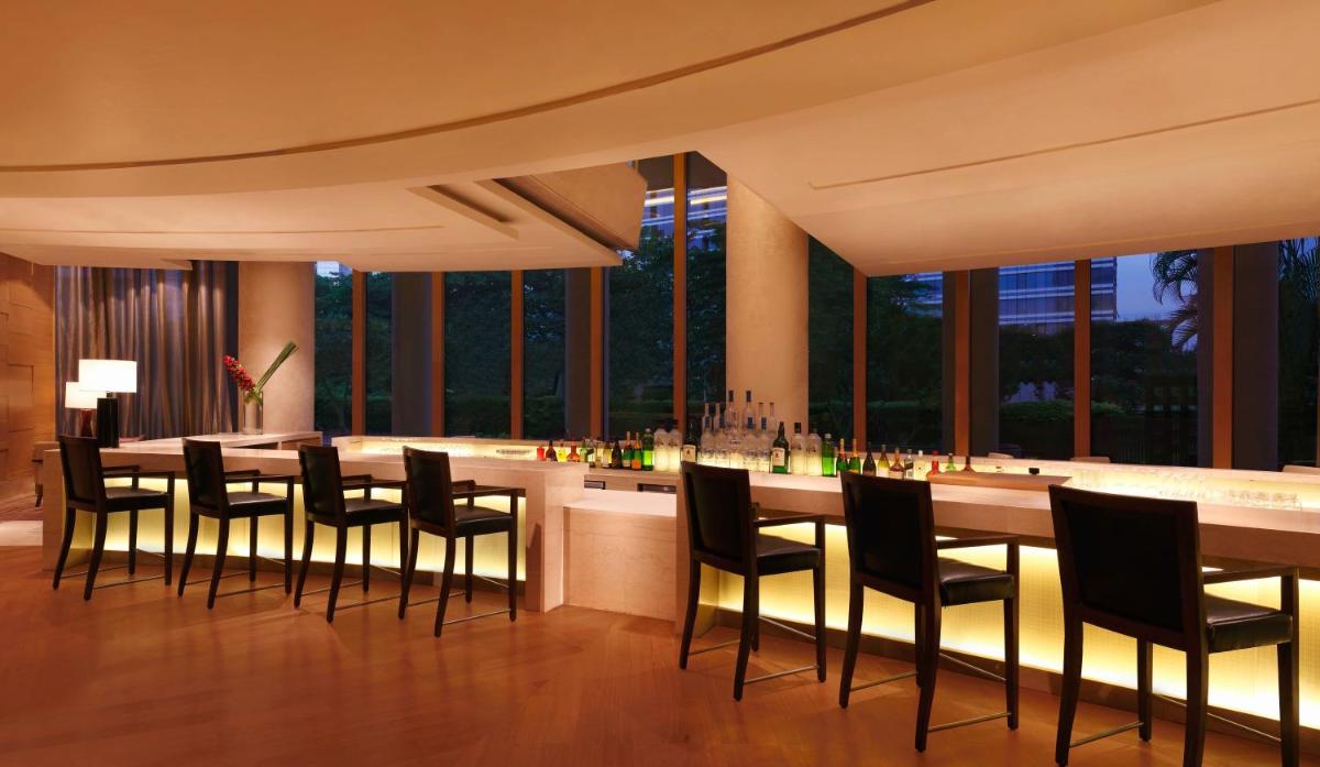 a dining room with a bar with black chairs at Trident Bandra Kurla in Mumbai a dining room with a bar with black chairs at Trident Bandra Kurla in Mumbai
