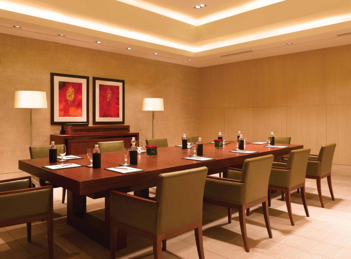 a conference room with a large wooden table and chairs at Trident Bandra Kurla in Mumbai a conference room with a large wooden table and chairs at Trident Bandra Kurla in Mumbai