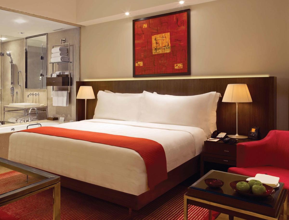 a bedroom with a large bed and a red chair at Trident Bandra Kurla in Mumbai a bedroom with a large bed and a red chair at Trident Bandra Kurla in Mumbai