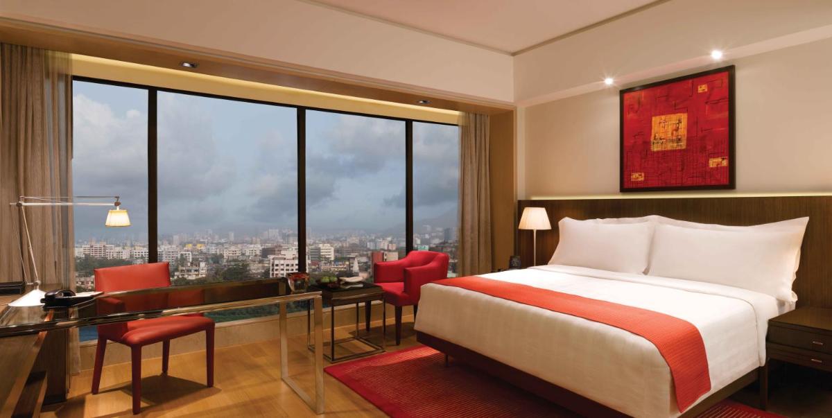 a bedroom with a bed and a desk and a large window at Trident Bandra Kurla in Mumbai +58 photos a bedroom with a bed and a desk and a large window at Trident Bandra Kurla in Mumbai +58 photos
