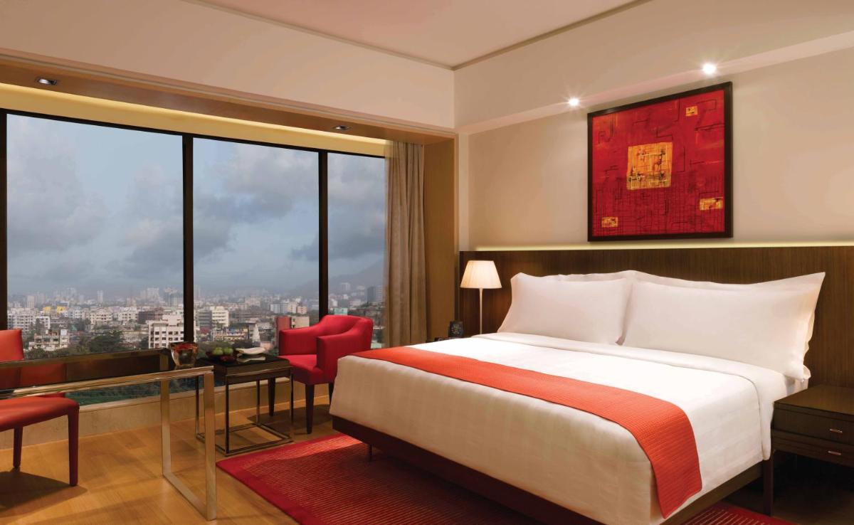 a hotel room with a bed and a large window at Trident Bandra Kurla in Mumbai a hotel room with a bed and a large window at Trident Bandra Kurla in Mumbai