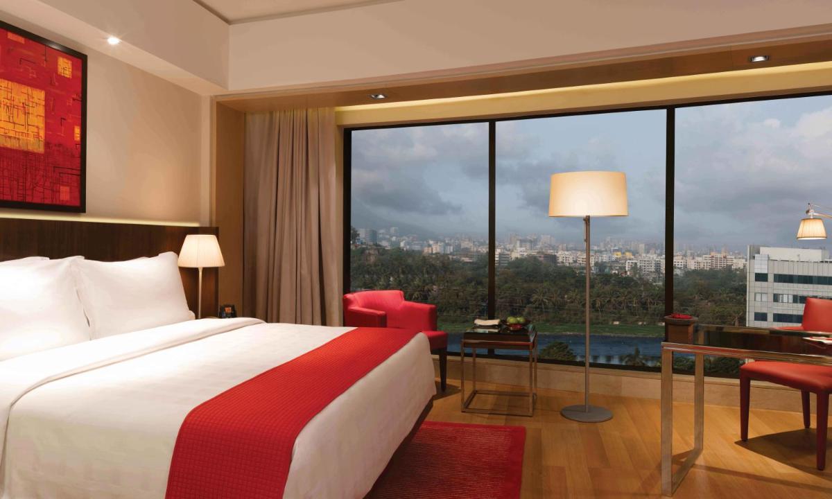 a hotel room with a bed and a large window at Trident Bandra Kurla in Mumbai a hotel room with a bed and a large window at Trident Bandra Kurla in Mumbai