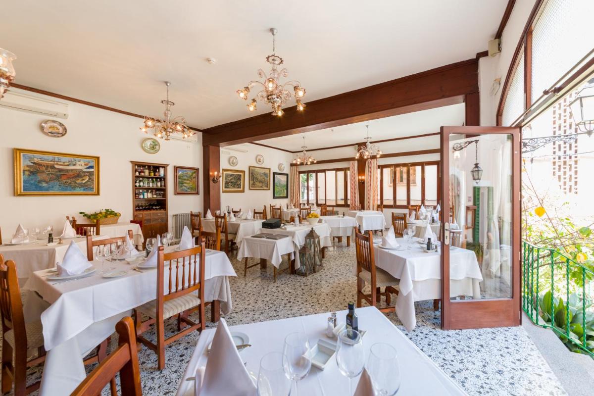 Un comedor con mesas y sillas blancas. en Hotel El Guía, en Sóller
