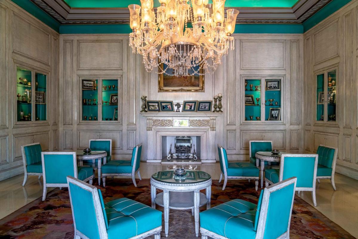 a dining room with tables and chairs and a chandelier at Rajmahal Palace RAAS in Jaipur