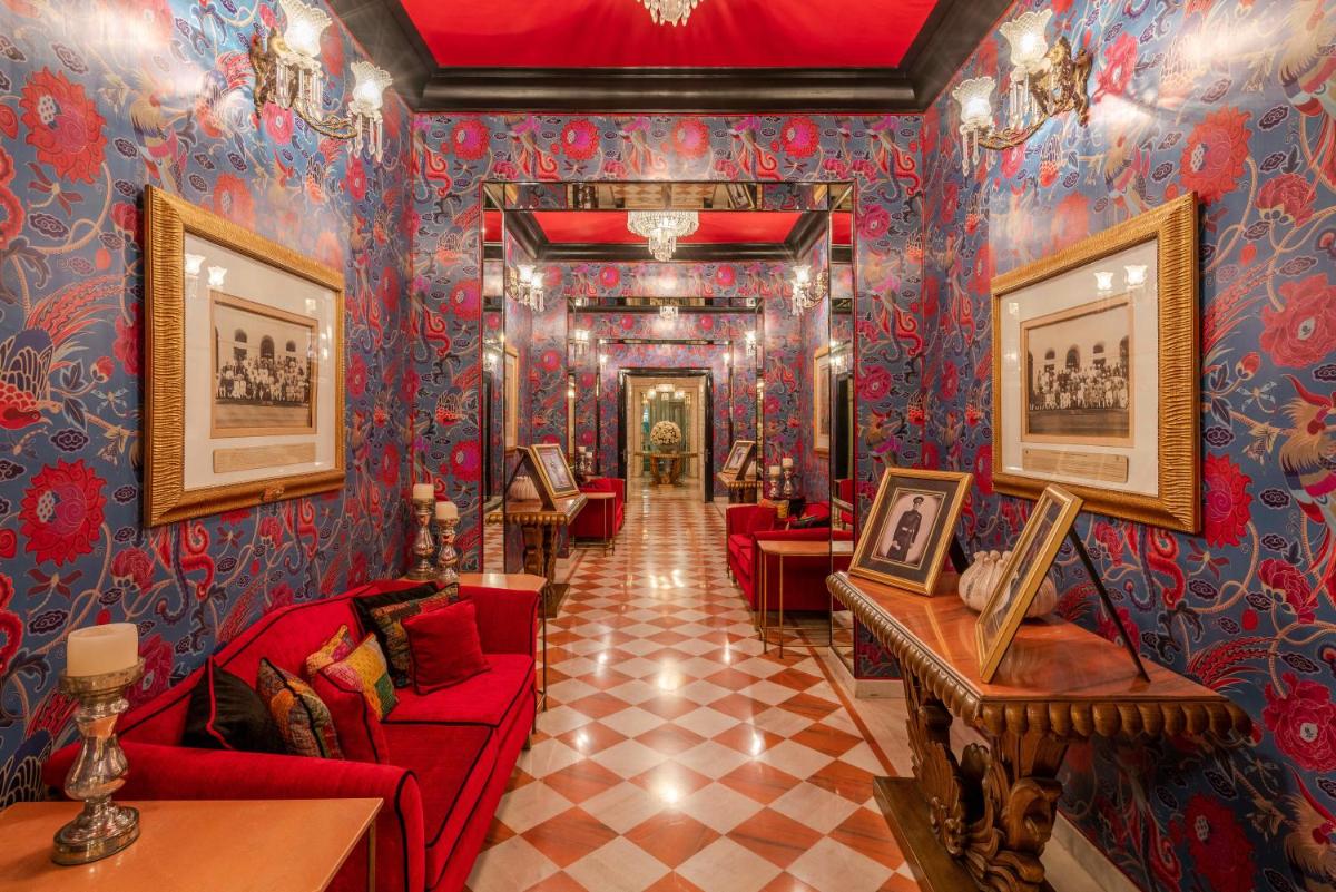 a living room with red couches and blue wallpaper at Rajmahal Palace RAAS in Jaipur