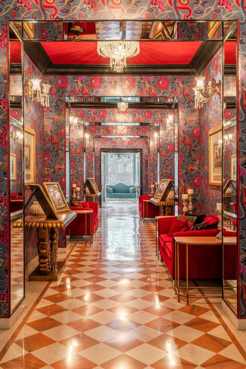 a room with red couches and a wall covered in wallpaper at Rajmahal Palace RAAS in Jaipur