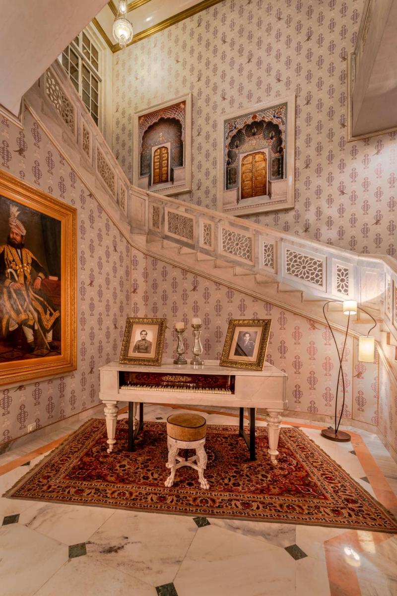a living room with a piano in a room with wallpaper at Rajmahal Palace RAAS in Jaipur