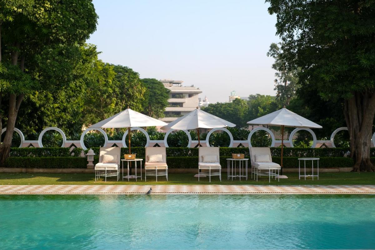 a group of chairs and umbrellas next to a pool at Rajmahal Palace RAAS in Jaipur