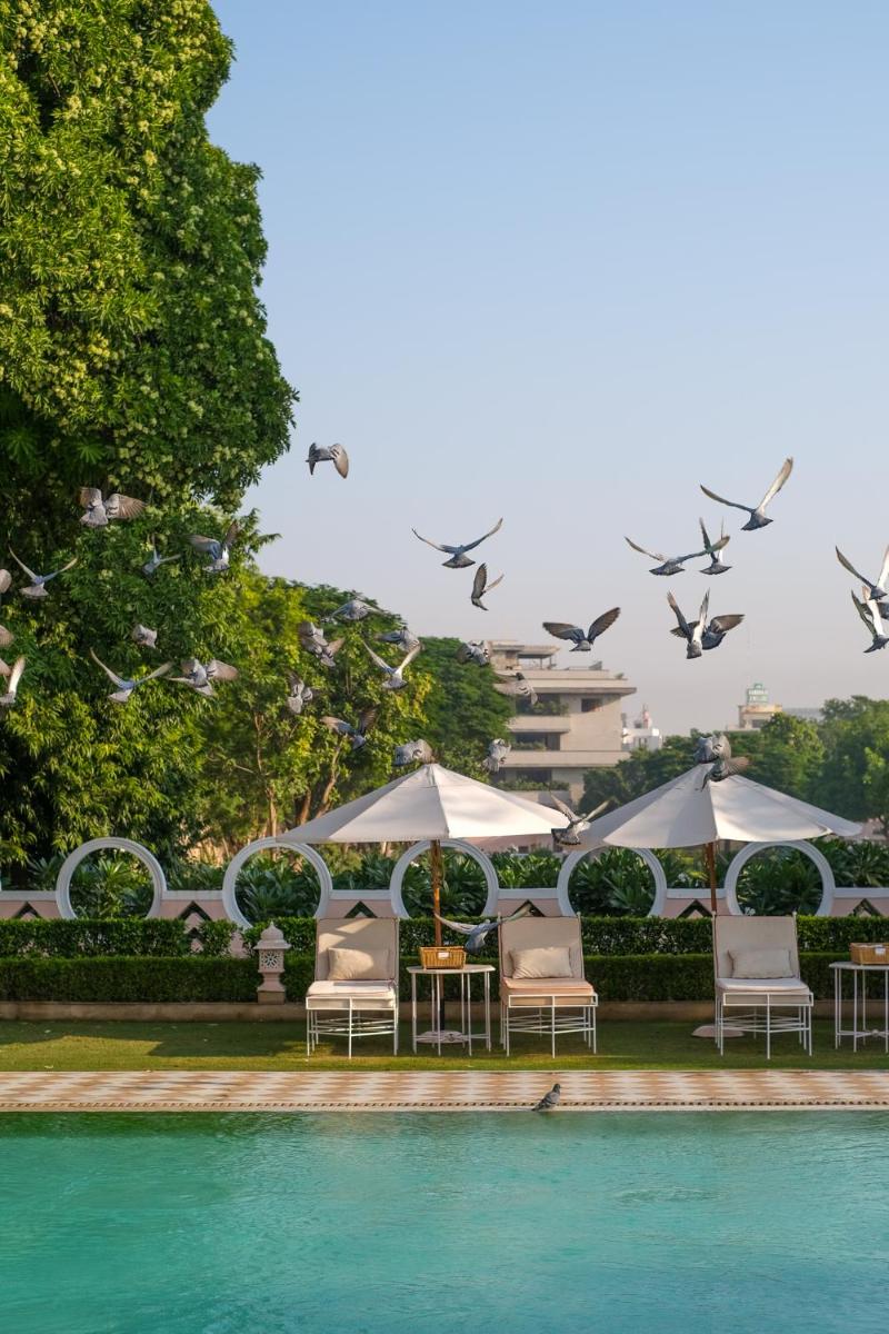 a group of chairs and umbrellas next to a pool at Rajmahal Palace RAAS in Jaipur