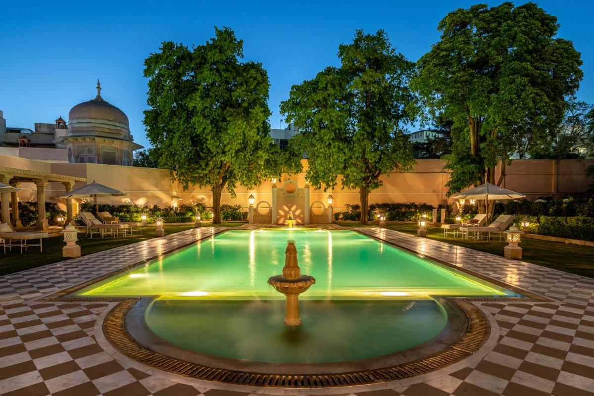 a pool with a fountain in front of a building at Rajmahal Palace RAAS in Jaipur