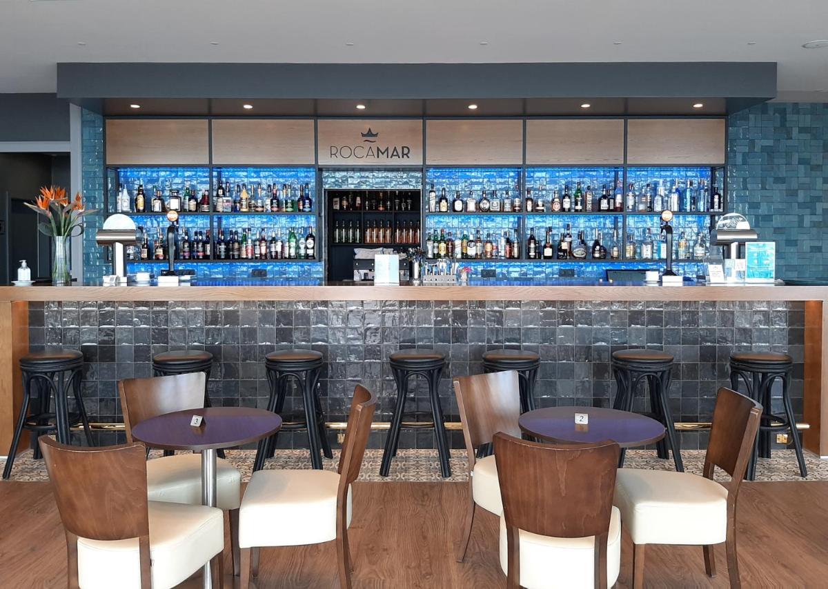 um bar com mesas e cadeiras em um restaurante em Hotel Roca Mar no Caniço
