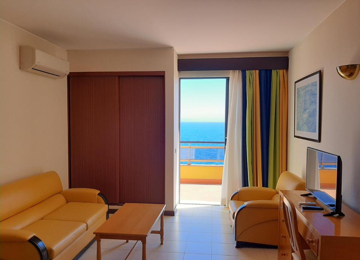 uma sala de estar com um sofá e vista para o oceano em Hotel Cais da Oliveira no Caniço