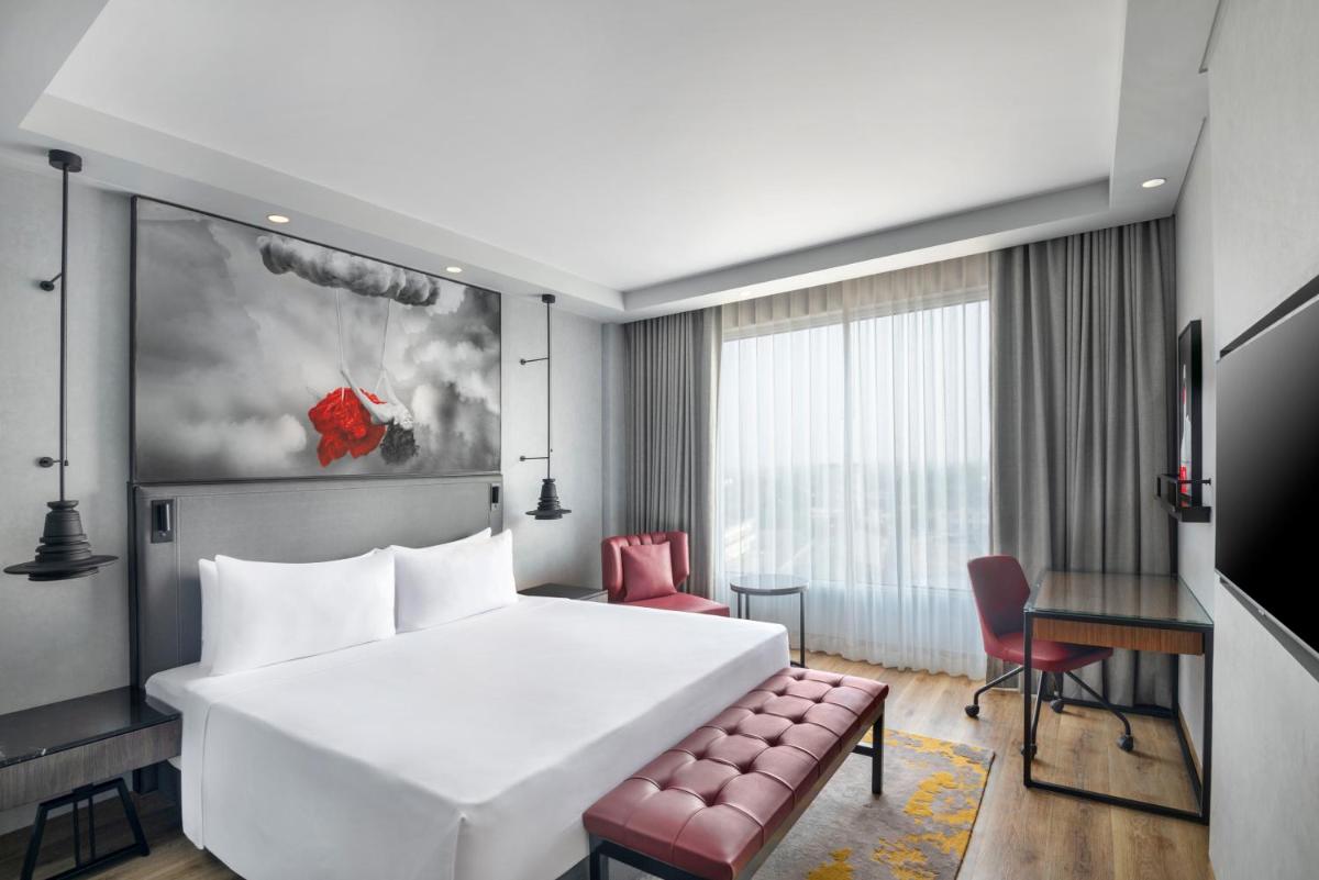 a hotel room with a large white bed and a desk at Radisson RED Chandigarh Mohali in Chandīgarh