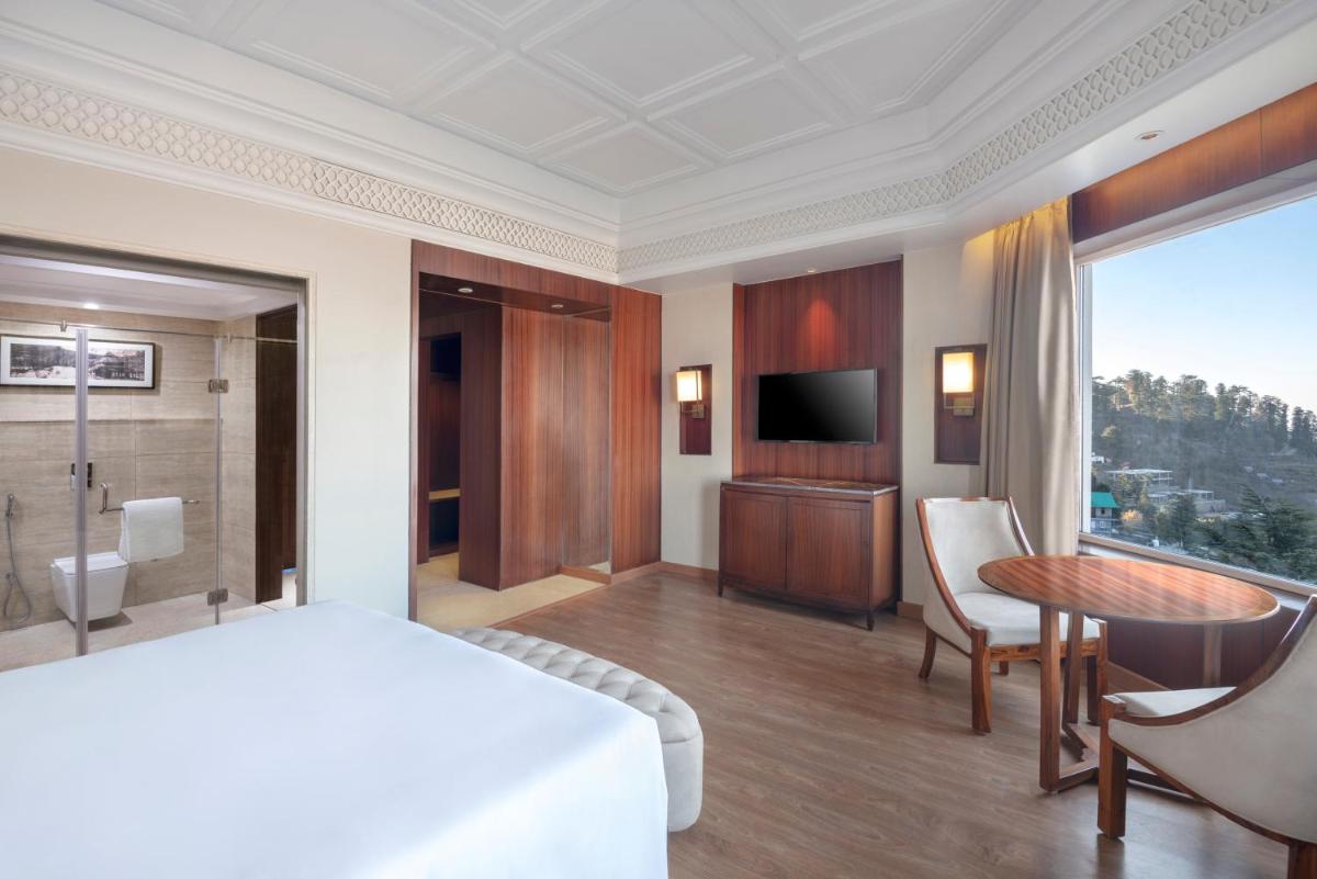 a bedroom with a bed and a table and a television at Radisson Kufri in Shimla