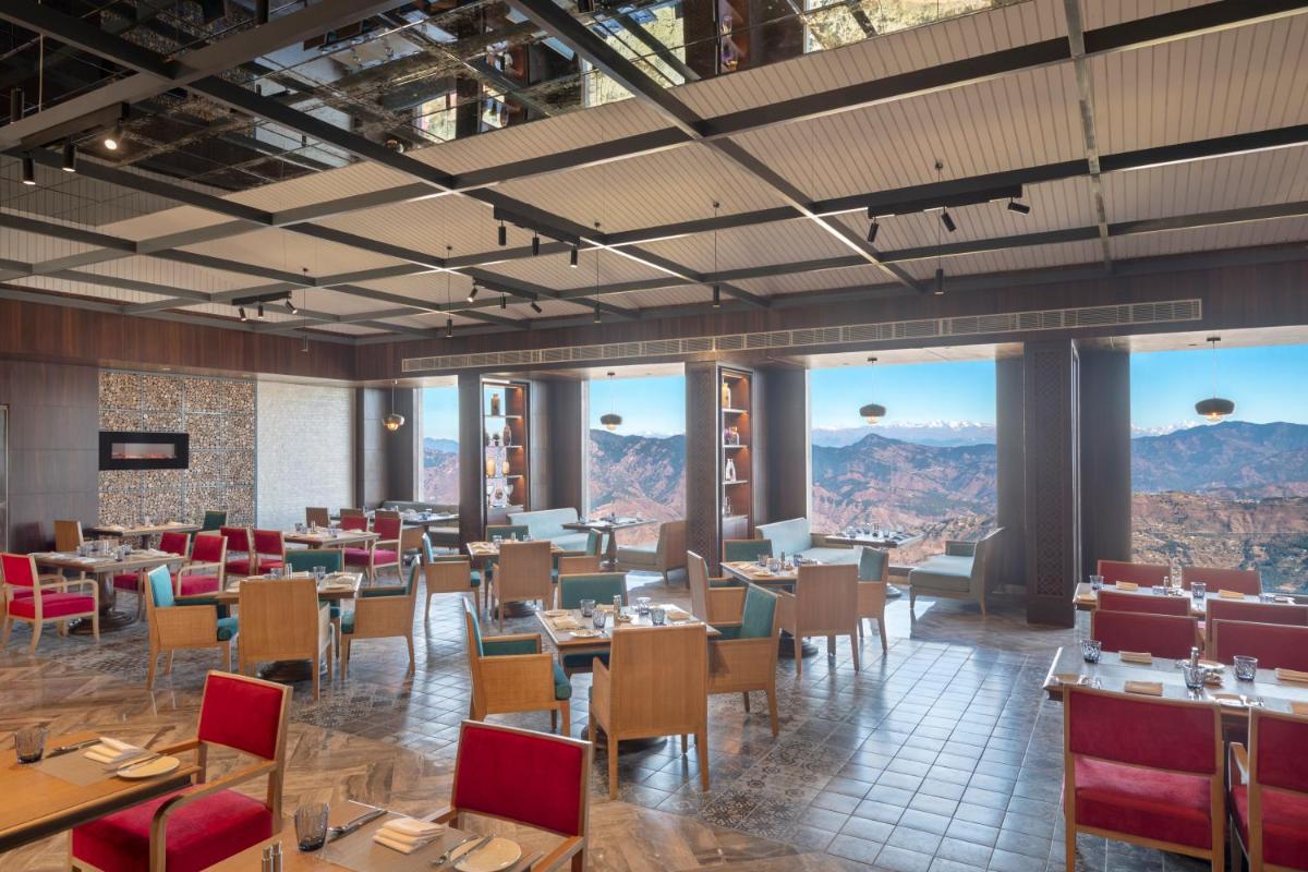 a restaurant with tables and chairs and mountains in the background at Radisson Kufri in Shimla