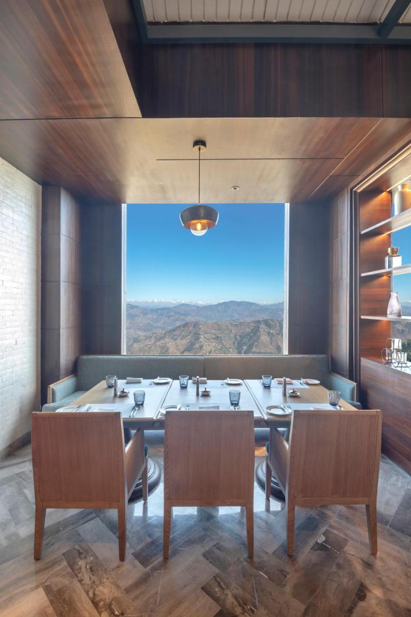 a dining room with a table and chairs and a large window at Radisson Kufri in Shimla