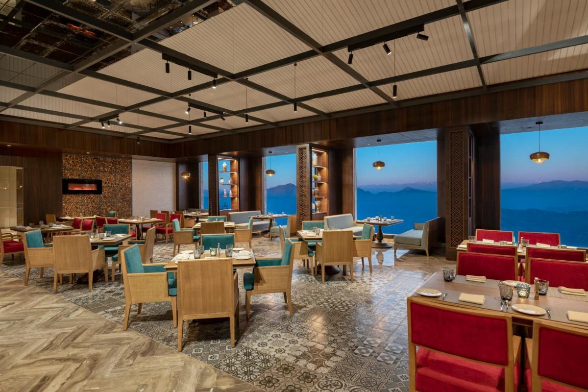 a restaurant with tables and chairs and large windows at Radisson Kufri in Shimla