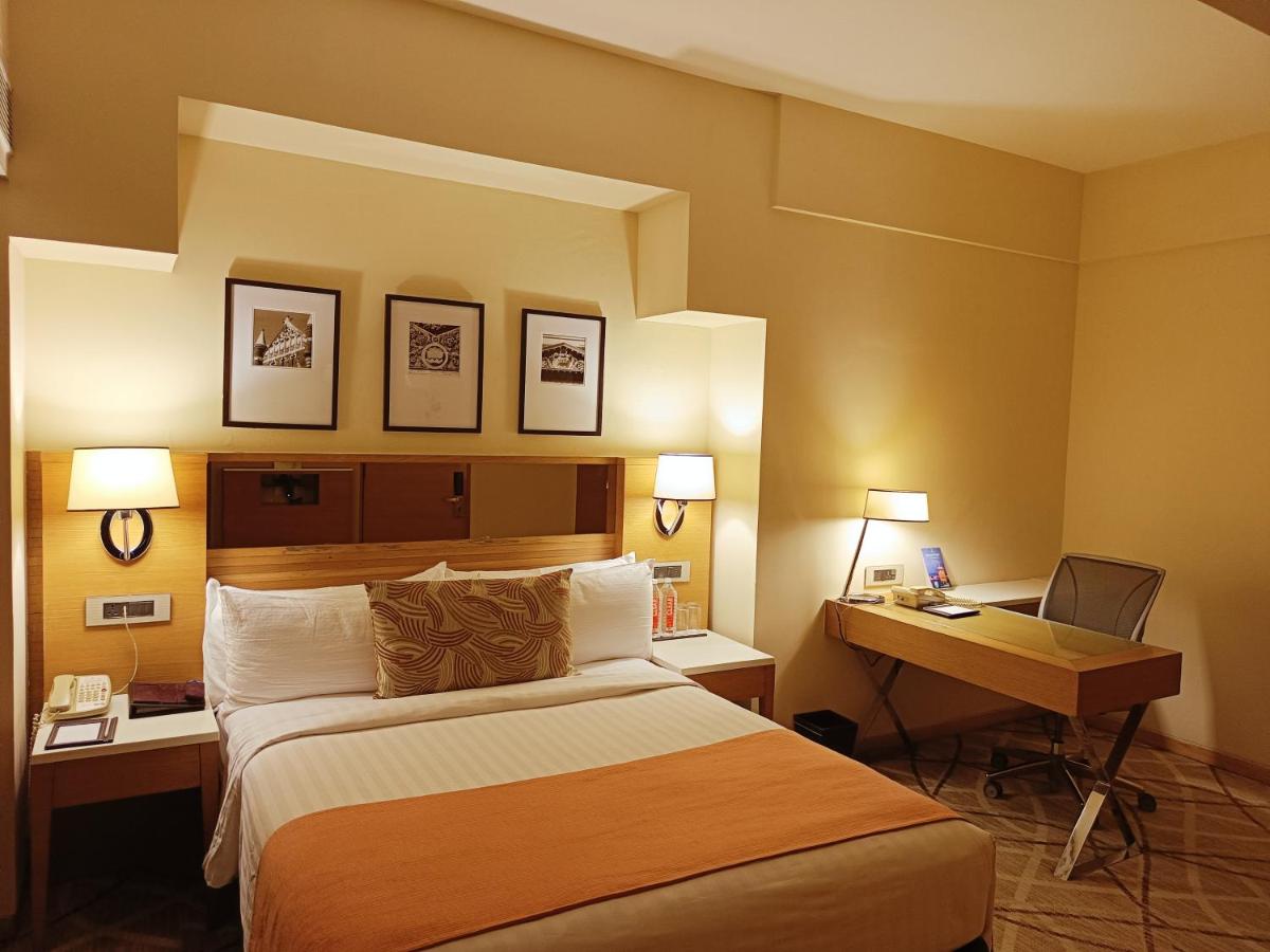 a hotel room with a bed and a desk at Hotel Marine Plaza in Mumbai