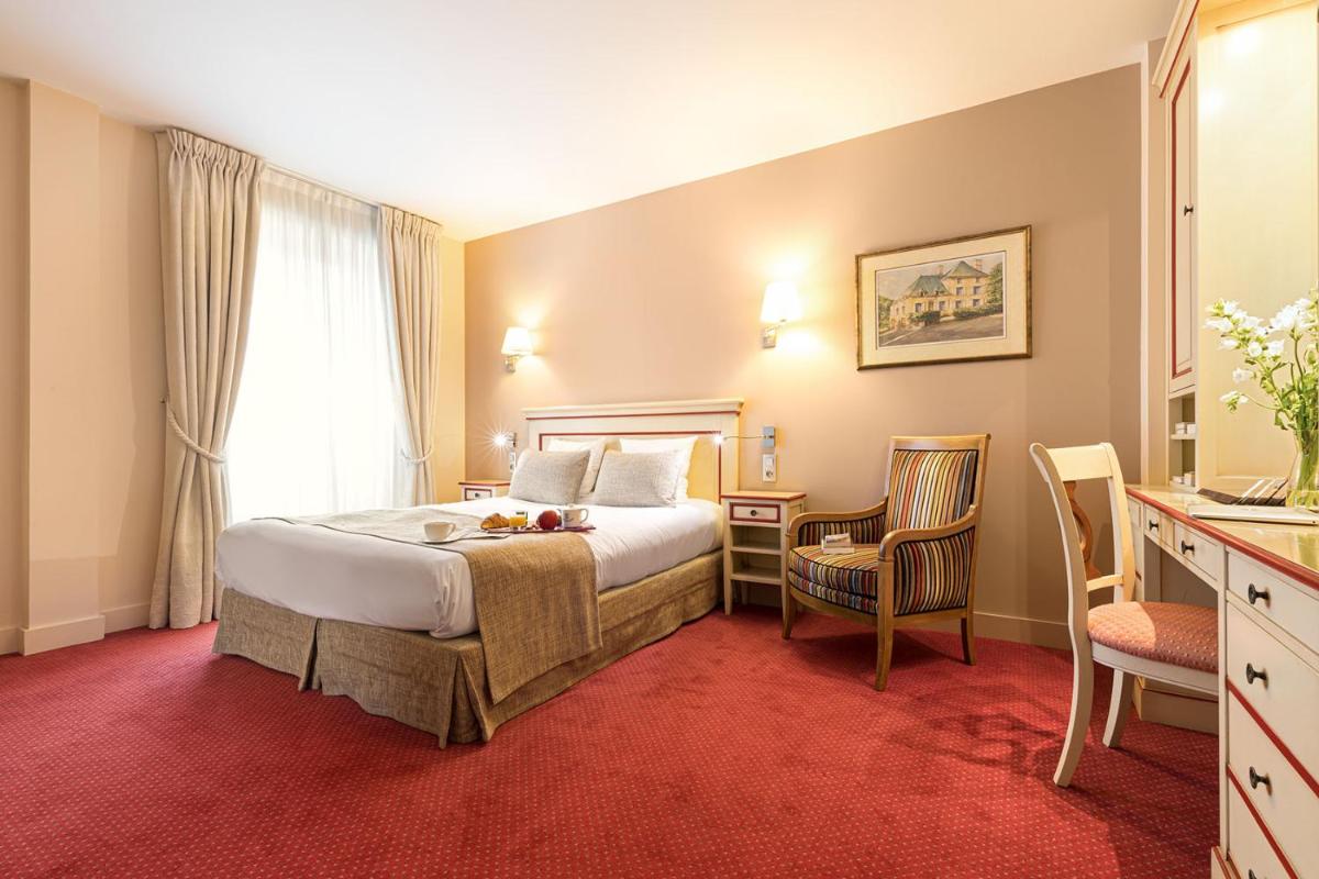 une chambre d'hôtel avec un lit, une table et des chaises dans l'établissement Hôtel Spa Thermalia, à Châtel-Guyon 28 autres photos