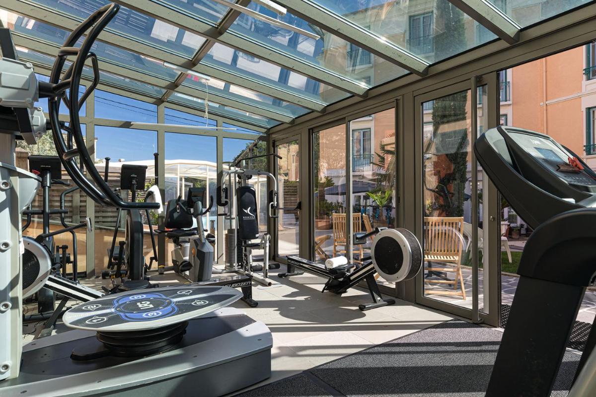 - une salle de sport avec des équipements de cardio-training dans un bâtiment doté de fenêtres dans l'établissement Hôtel Spa Thermalia, à Châtel-Guyon
