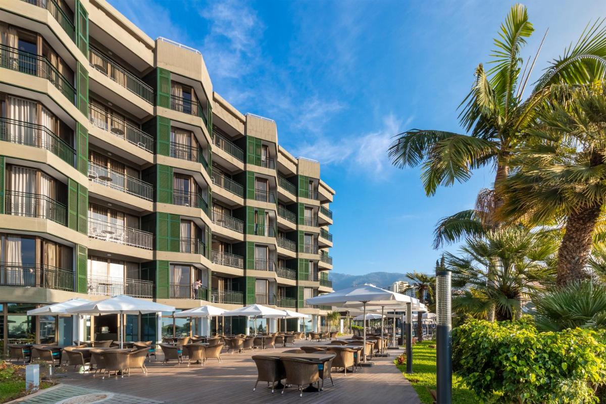 um hotel com mesas e guarda-sóis em frente a um edifício em Enotel Magnólia no Funchal