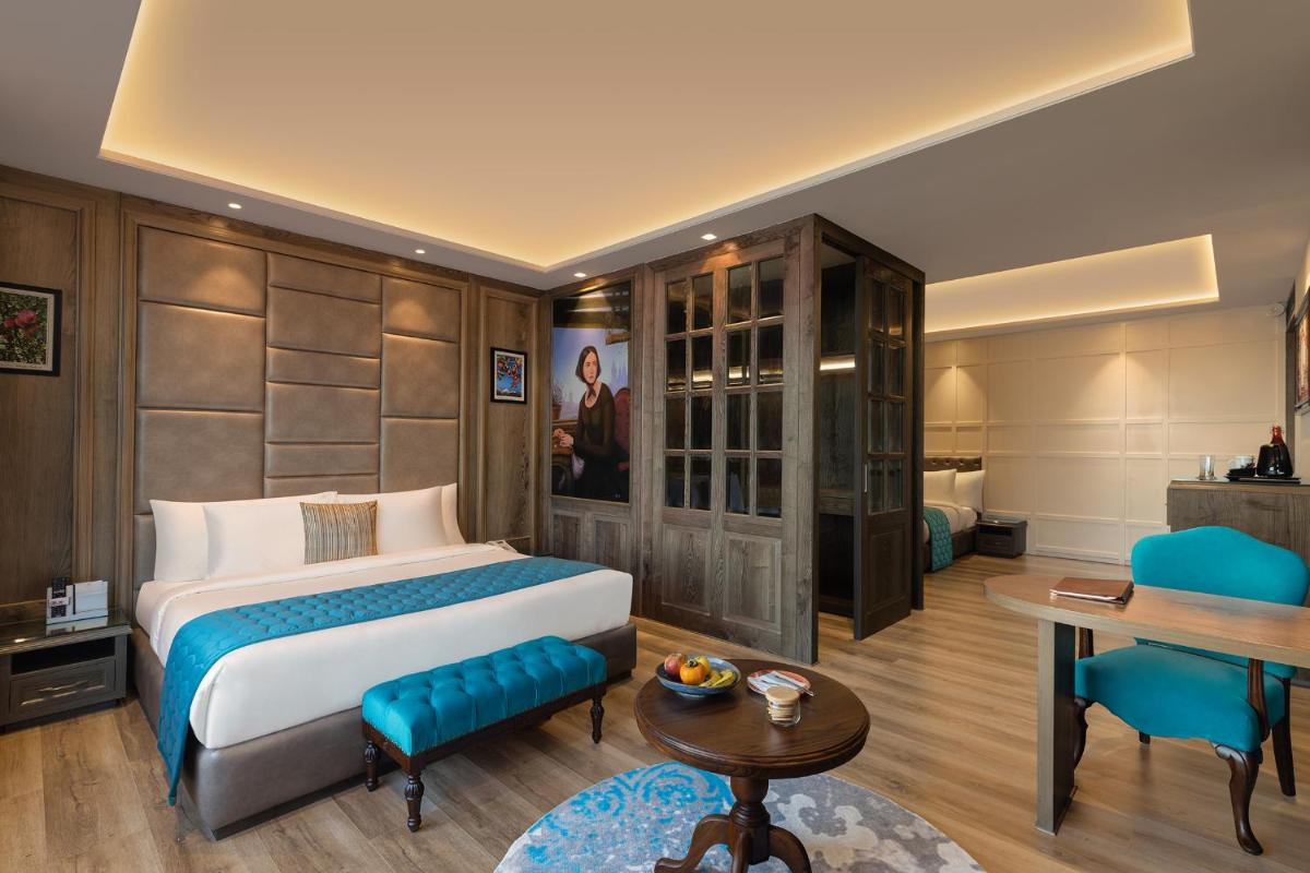 a hotel room with a bed and a table and chairs at WelcomHeritage Elysium Resort & Spa in Shimla