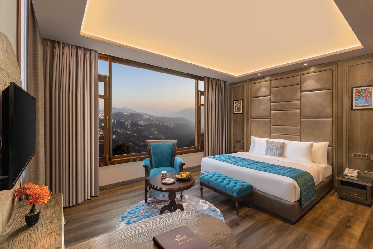 a hotel room with a bed and a large window at WelcomHeritage Elysium Resort & Spa in Shimla