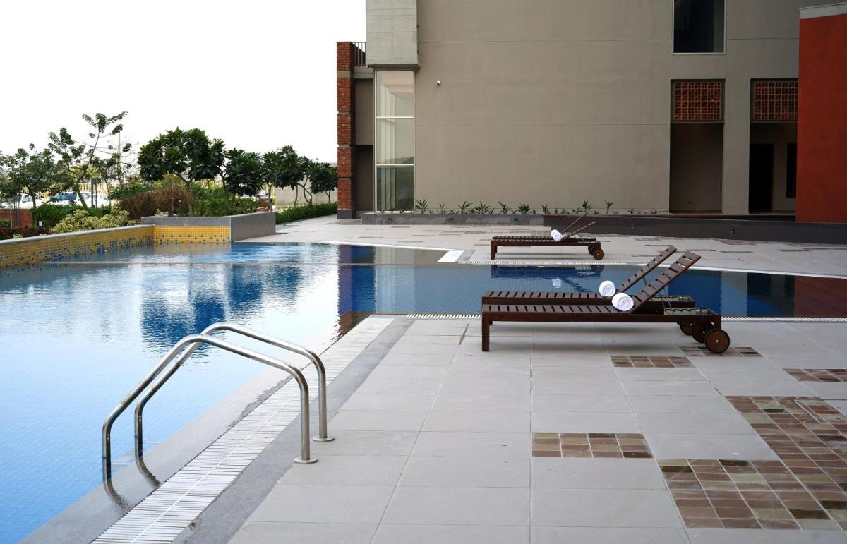 a swimming pool with a bench next to a building at The Centrum in Lucknow
