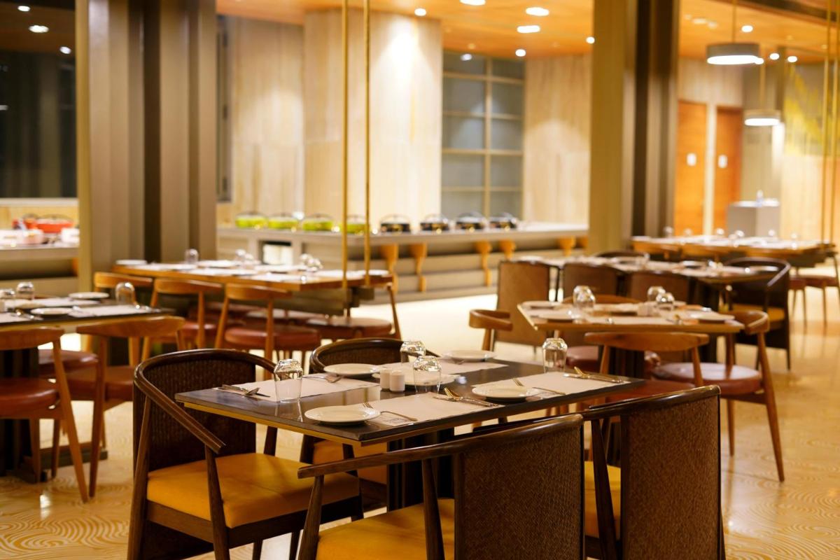 a dining room with tables and chairs in a restaurant at The Centrum in Lucknow