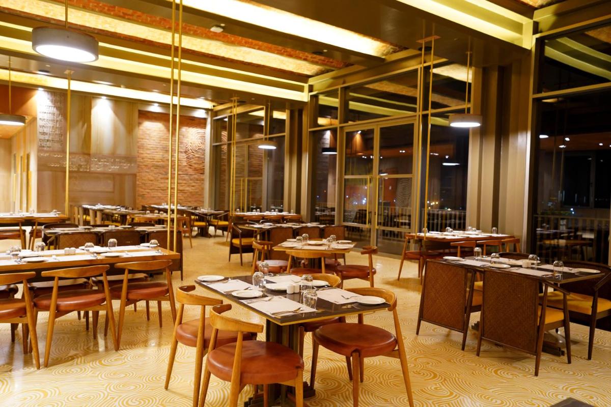 a restaurant with tables and chairs in a room at The Centrum in Lucknow
