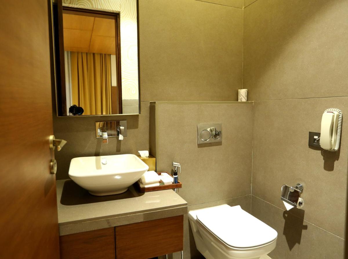 a bathroom with a sink and a toilet and a mirror at The Centrum in Lucknow