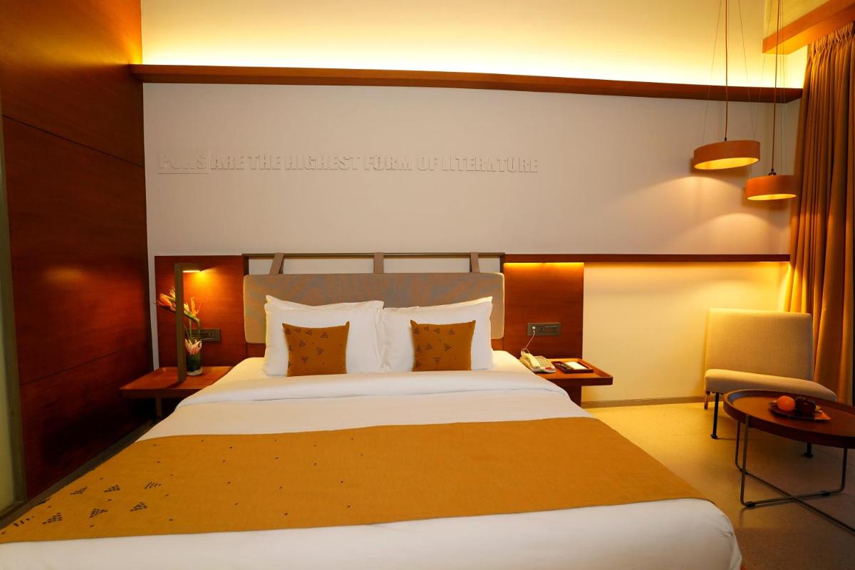 a hotel room with a large bed and a chair at The Centrum in Lucknow