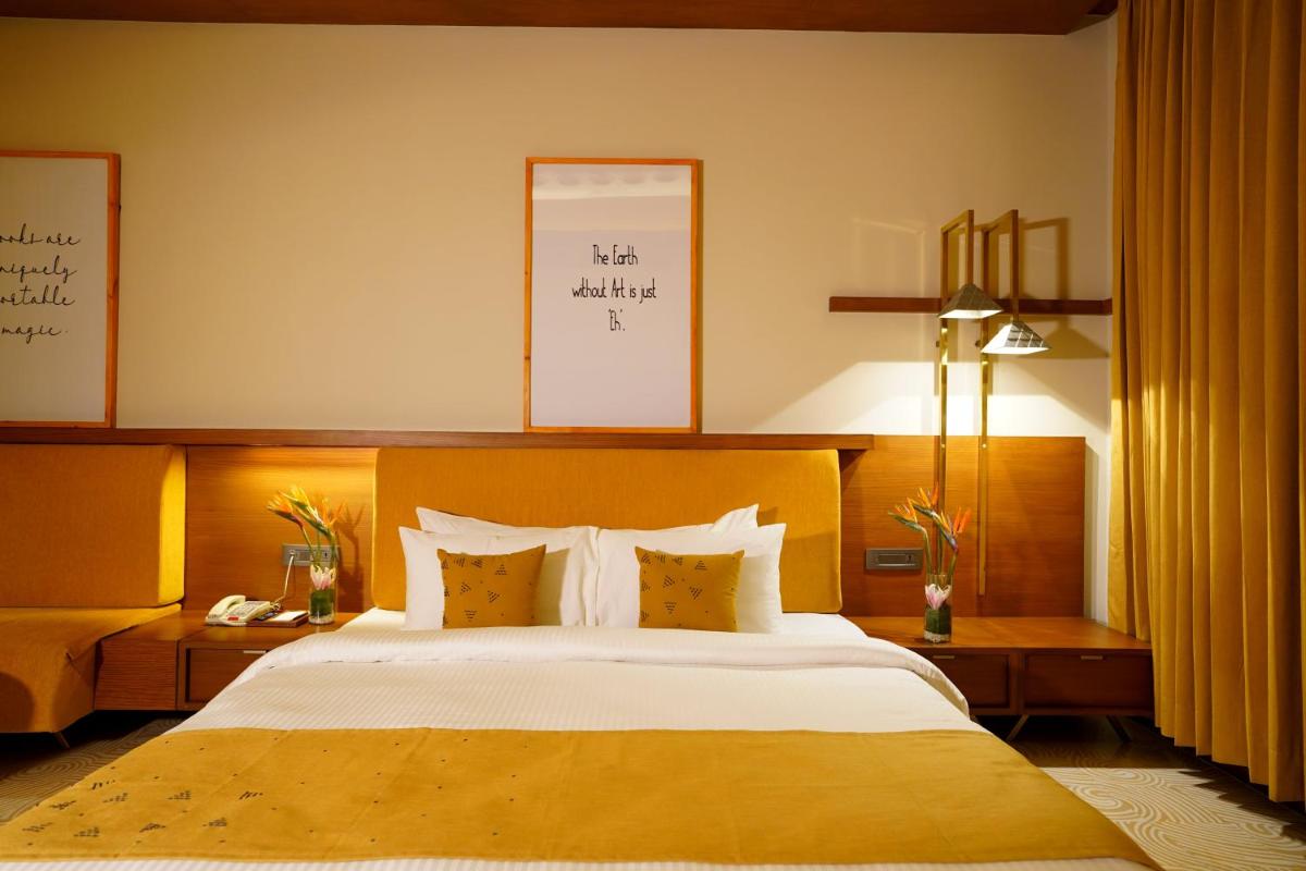 a bedroom with a large bed with white sheets and pillows at The Centrum in Lucknow