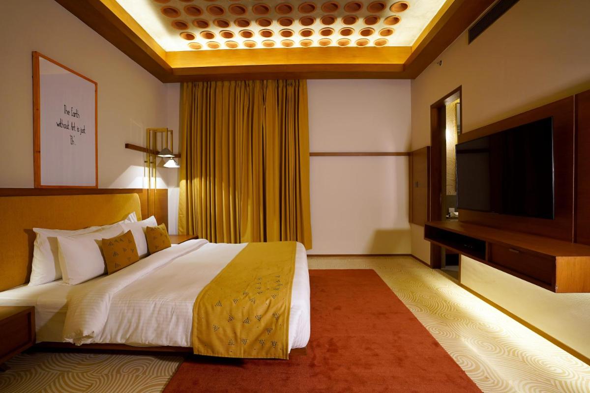 a hotel room with a bed and a flat screen tv at The Centrum in Lucknow