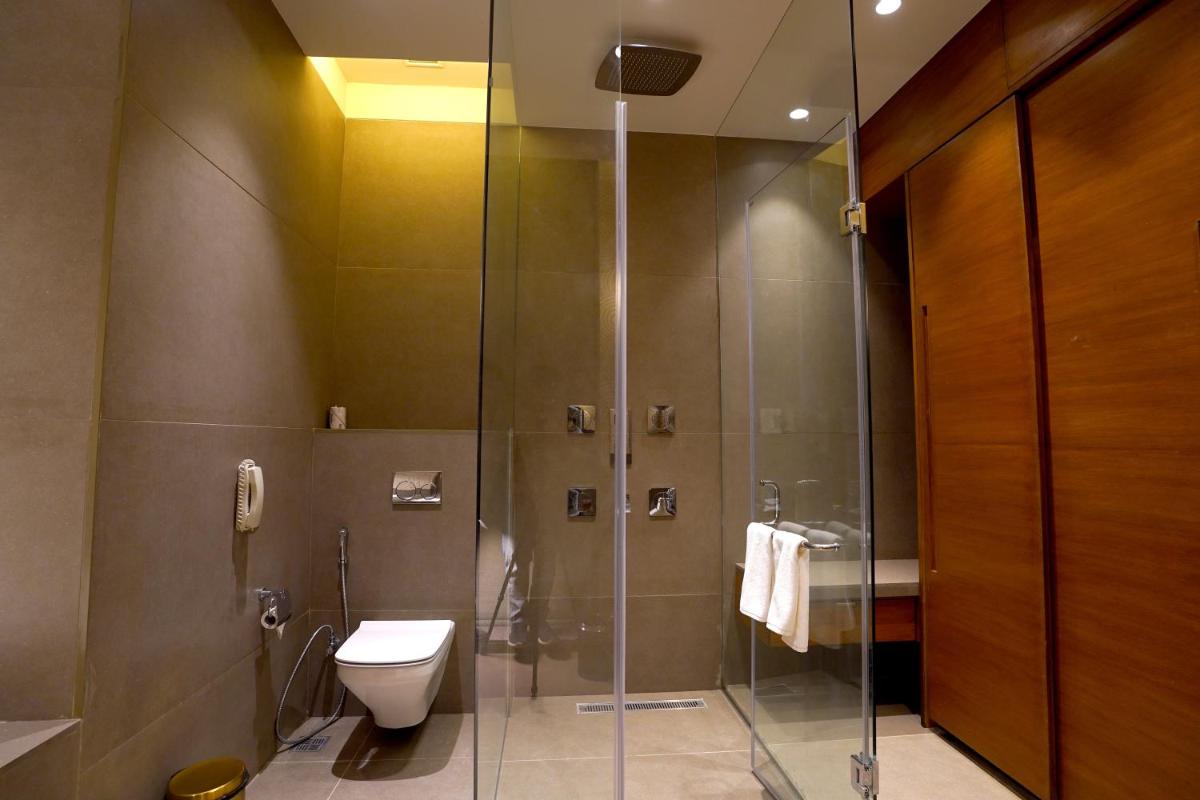 a bathroom with a toilet and a glass shower at The Centrum in Lucknow