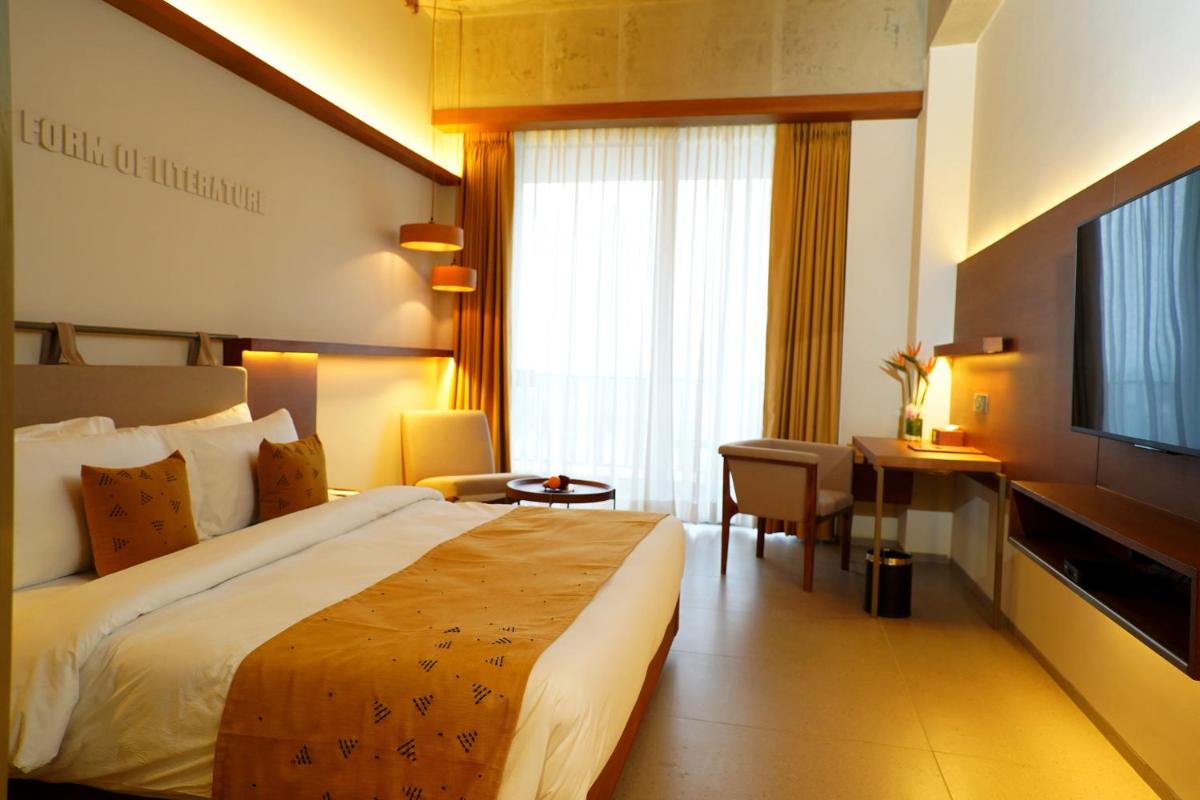 a hotel room with a bed and a desk and a television at The Centrum in Lucknow