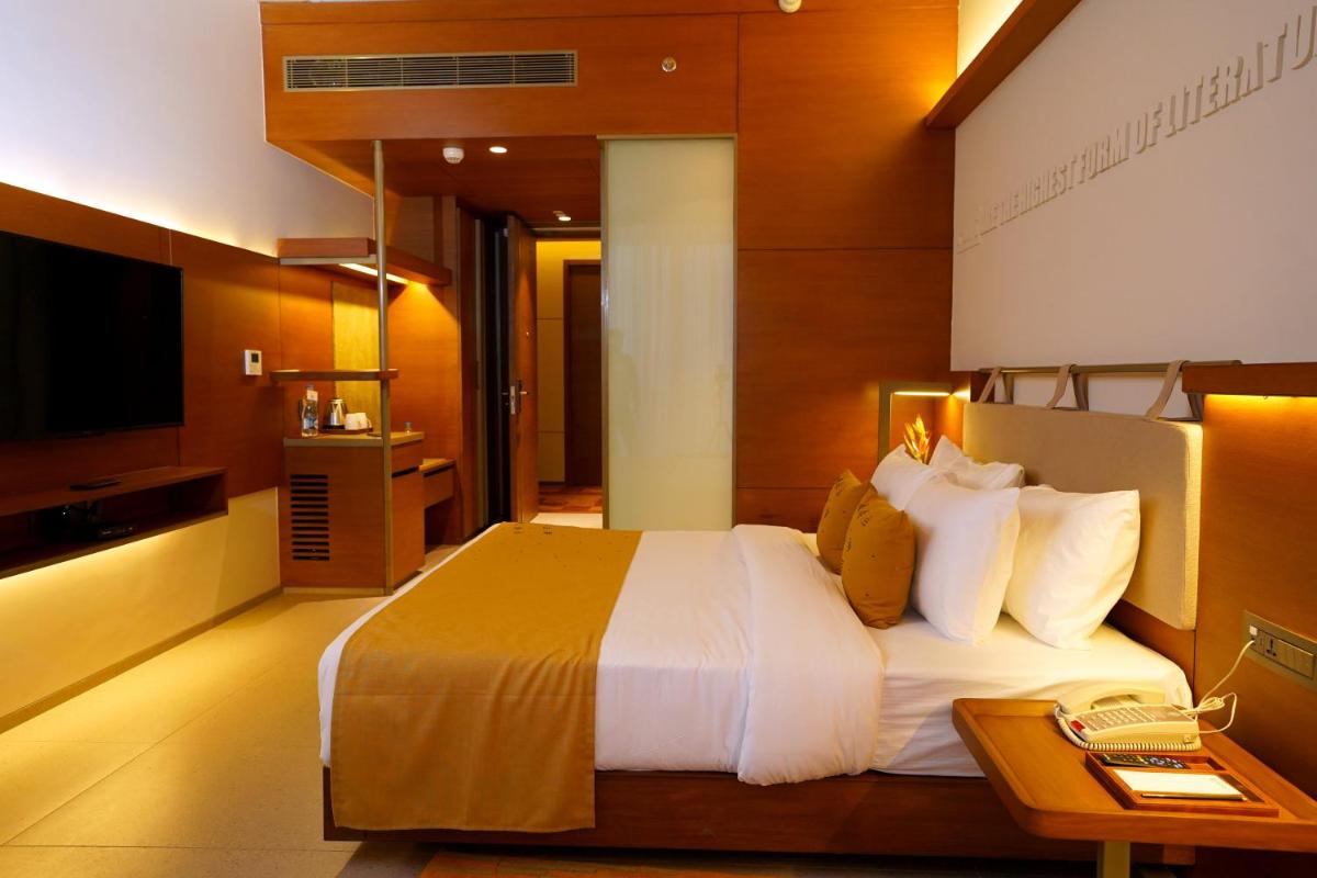 a hotel room with a large bed and a television at The Centrum in Lucknow