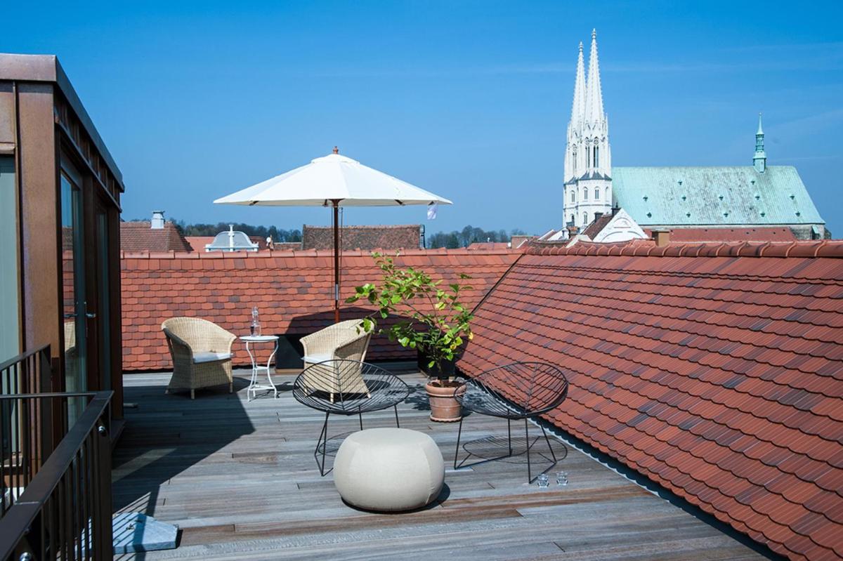 eine Terrasse mit Stühlen und einem Sonnenschirm auf einem Dach in der Unterkunft Emmerich Hotel Görlitz in Görlitz eine Terrasse mit Stühlen und einem Sonnenschirm auf einem Dach in der Unterkunft Emmerich Hotel Görlitz in Görlitz