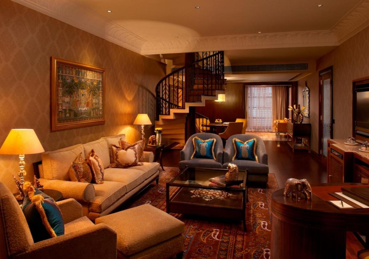 a living room with a couch and chairs and a staircase at The Leela Palace Udaipur in Udaipur