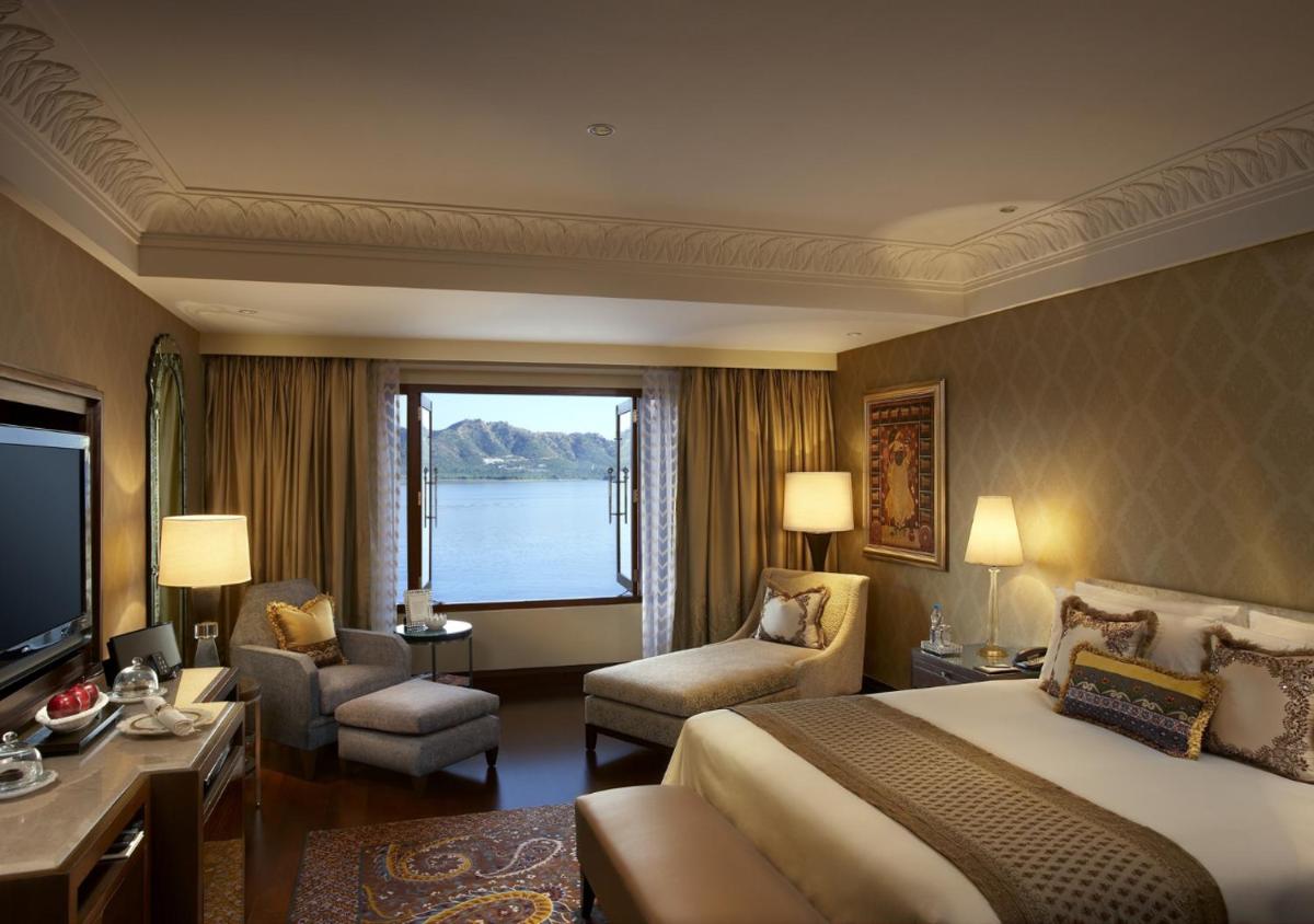 a hotel room with a bed and a large window at The Leela Palace Udaipur in Udaipur
