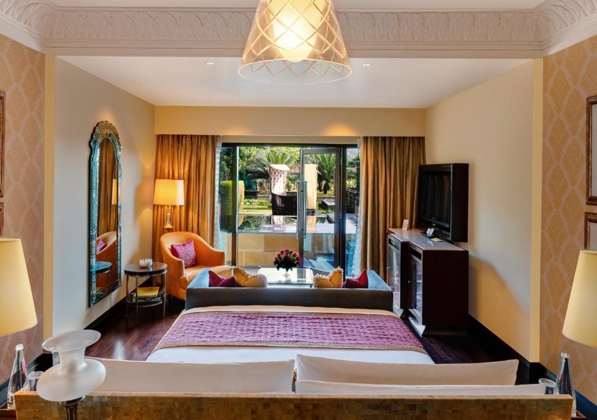 a bedroom with a large bed and a living room at The Leela Palace Udaipur in Udaipur