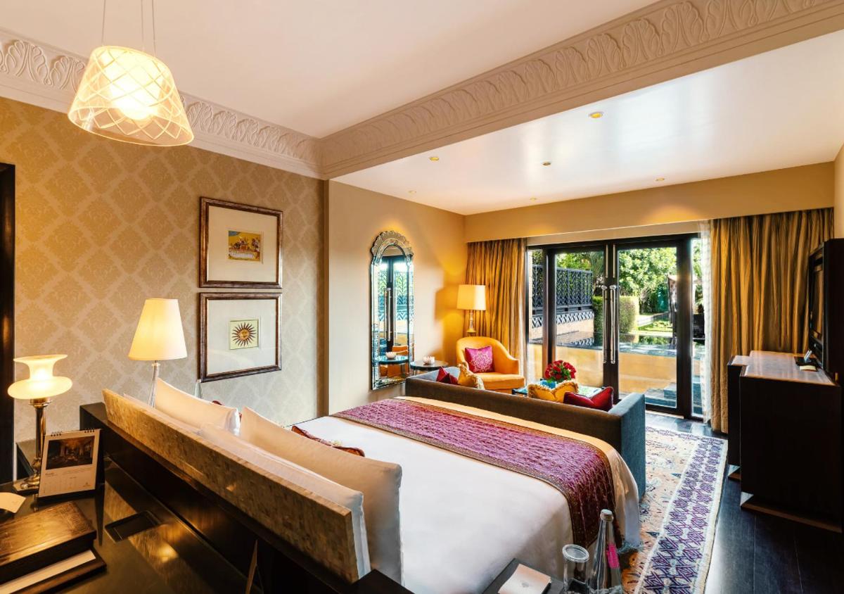 a hotel room with a bed and a large window at The Leela Palace Udaipur in Udaipur