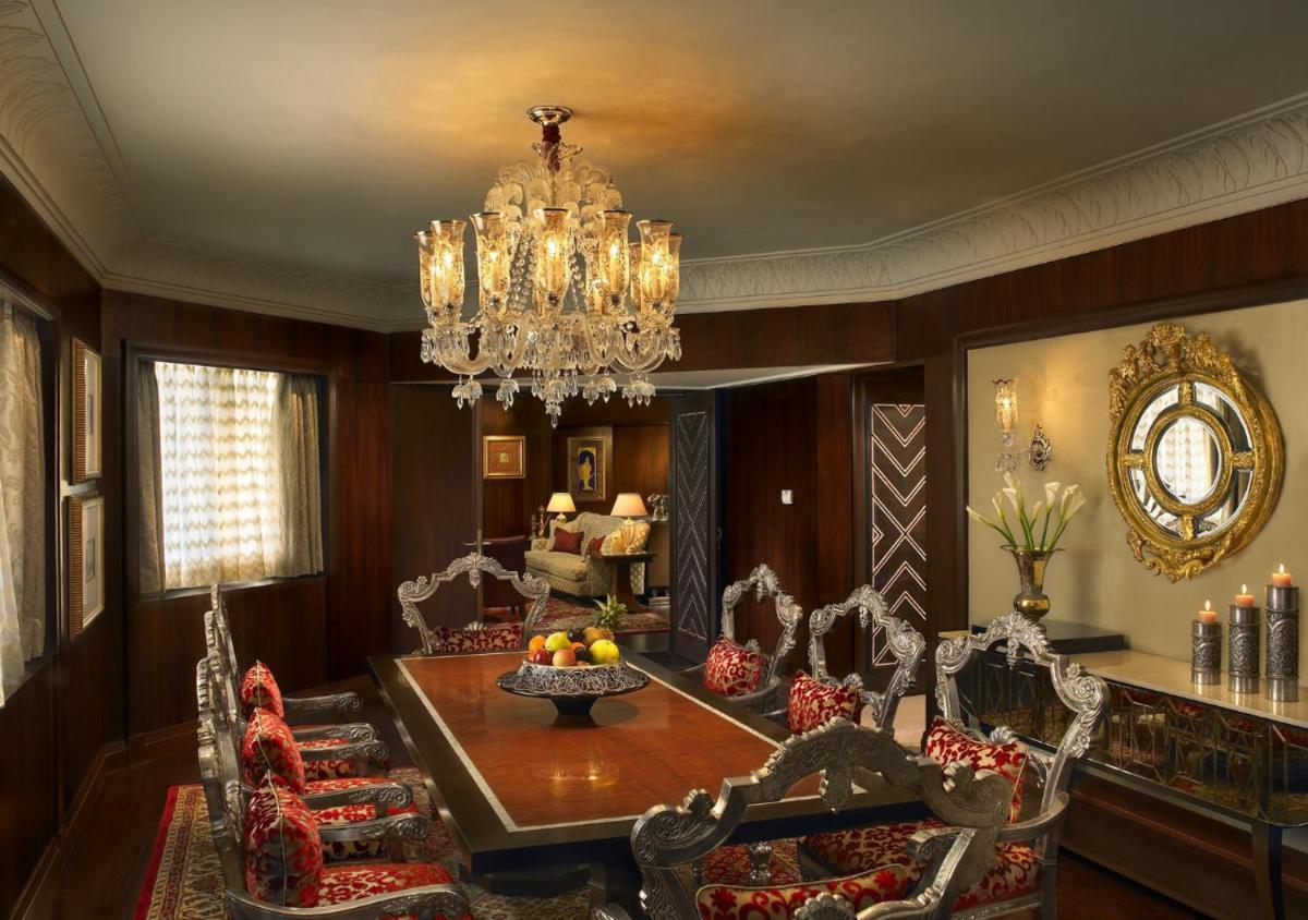 a dining room with a table and chairs and a chandelier at The Leela Palace Udaipur in Udaipur