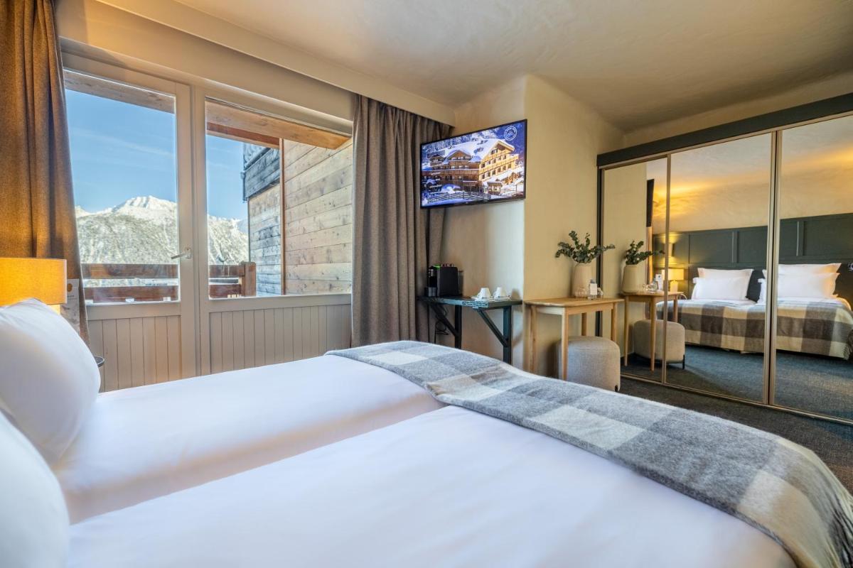 une chambre d'hôtel avec deux lits et une grande fenêtre dans l'établissement Grand Hôtel Courchevel 1850, à Courchevel